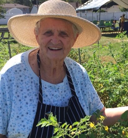 Portrait of smiling woman with sun hat in field of leafy green crops